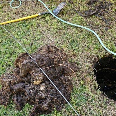 כלי עבודה וצינור ליד בור פתוח על דשא