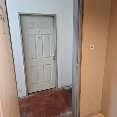 דלת וחדר עם רצפה אדומה וקירות לבנים