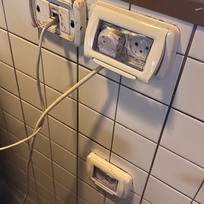 שקעים חשמליים על קיר אריחים עם כבלים מחוברים