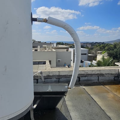 דוד שמש על גג עם צינור מחובר בשמיים בהירים