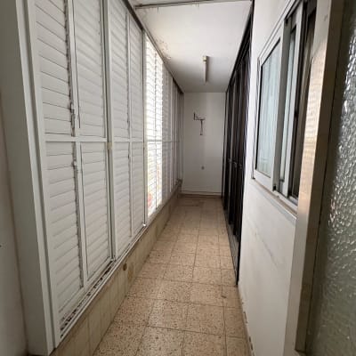 מסדרון עם חלונות תריסים לבנים וקירות לבנים