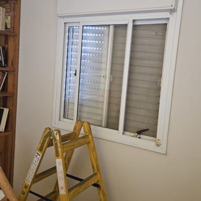 סולם ליד חלון עם תריסים לבנים