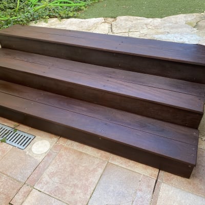 מדרגות עץ חומות בגינה עם ריצוף אבן