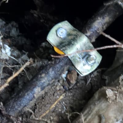 צינור מתכת עם תפסן וברגים באדמה