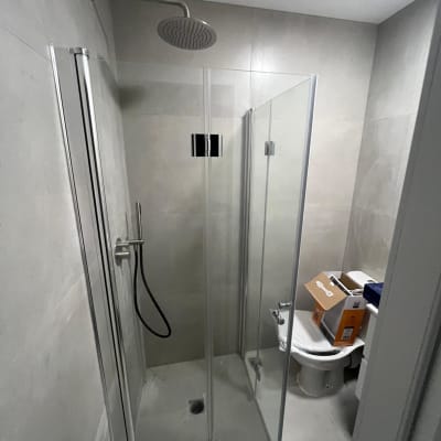 מקלחון זכוכית עם ראש מקלחת עגול וקירות אפורים