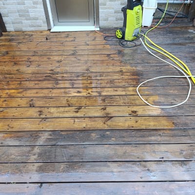 מרפסת עץ עם מכונת שטיפה וגליל צינור צהוב