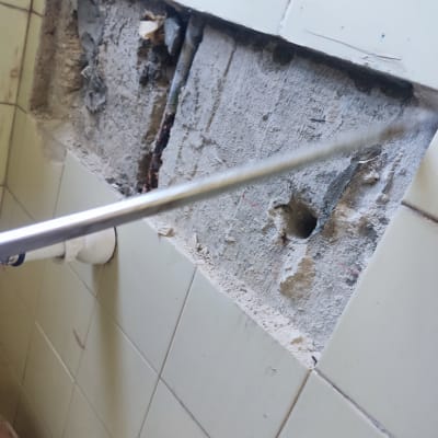 צינור מתכת ליד קיר עם חור ותשתית חשופה