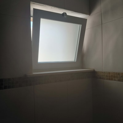 חלון ציר מאלומיניום לבן עם זכוכית חלבית בחדר רחצה