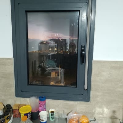 חלון עם תריסים במטבח, כוסות ותבלינים על השיש