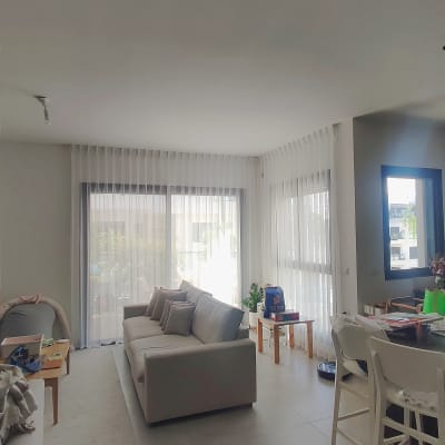 סלון עם וילונות לבנים על חלונות גדולים