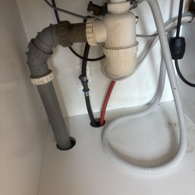 צנרת מתחת לכיור עם חיבורים וצינורות פלסטיק