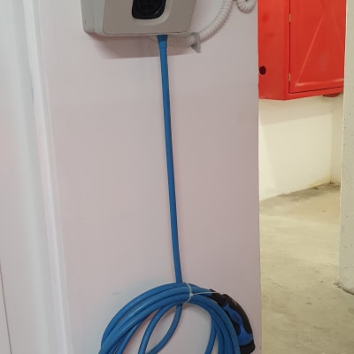 עמדת טעינה לרכב חשמלי עם כבל כחול תלוי