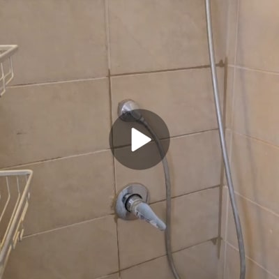 ברז מקלחת וצינור מקלחון מותקנים על קיר אריחים
