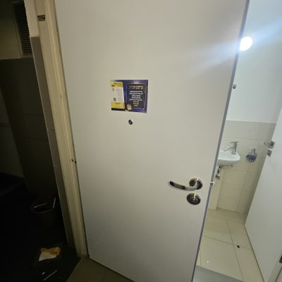 דלת לבנה עם ידית מתכת ומודעה מודבקת