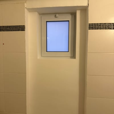 חלון קטן עם מסגרת אלומיניום בקיר לבן