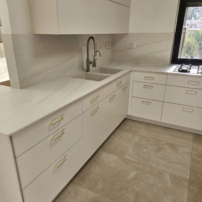 מטבח נקי עם ארונות לבנים וכיור נירוסטה