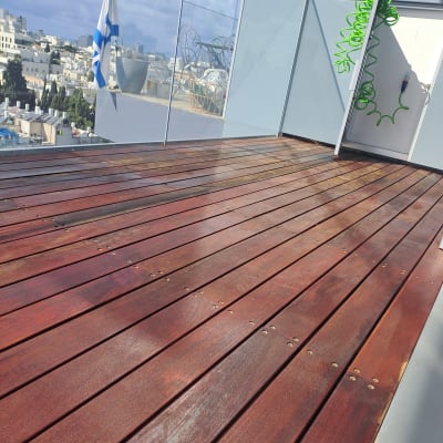 רצפת עץ חומה עם ברגים, צינור ירוק על קיר