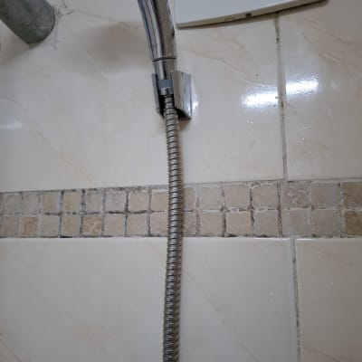 צינור מקלחת מתכת מחובר לקיר קרמיקה