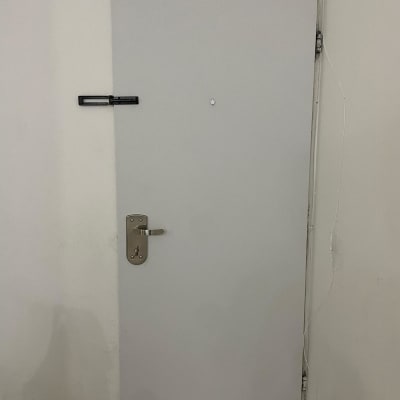 דלת לבנה עם ידית מתכת ובריח עליון