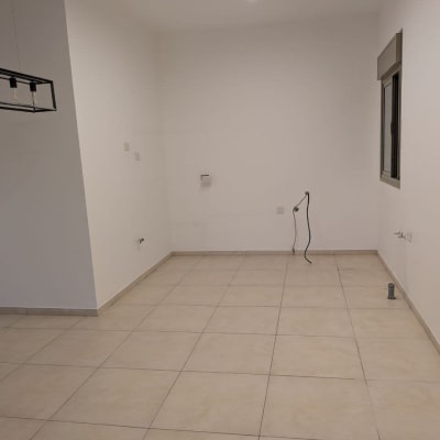 חדר ריק עם רצפת אריחים, קיר לבן ותאורה עליונה