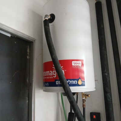 דוד שמש עם צינורות וחיבורים מותקנים על קיר