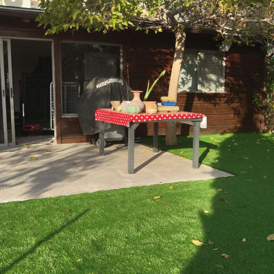 שולחן עם עציצים וכלי גינון על דשא סינתטי