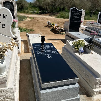 מצבות עם כיתוב ופרחים בבית קברות