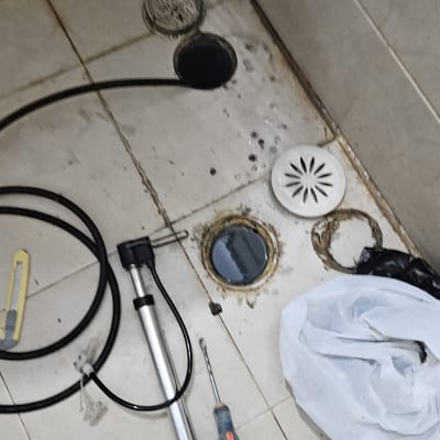 כלים לעבודה בצנרת וביוב על רצפת חדר אמבטיה