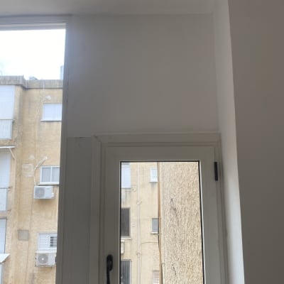 חלון עם ידית שחורה על רקע קיר חיצוני