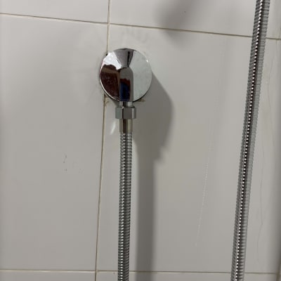 צינור מקלחת מחובר לקיר עם אריחים לבנים