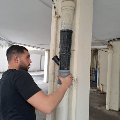 אדם מתקין צינור פלסטיק על עמוד בטון