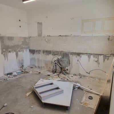 חדר בשיפוץ עם קירות חשופים וכלים על הרצפה