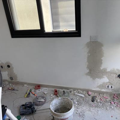 חדר עם קיר בתיקון וכלי עבודה על הרצפה