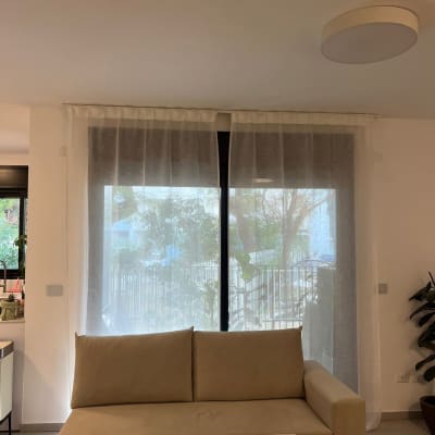 ספה מול חלון עם וילון לבן בסלון