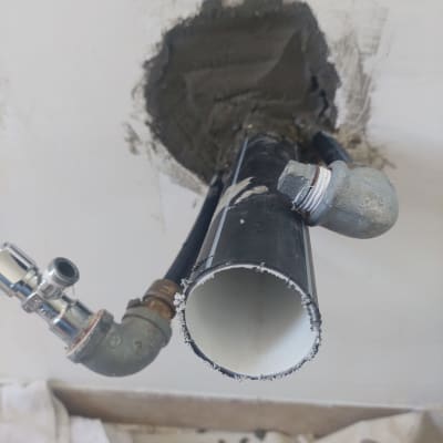 צינור שחור עם מחברים מתכתיים בקיר