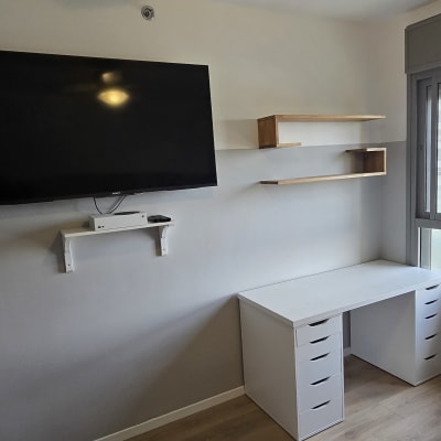 טלוויזיה תלויה על הקיר, מדפים ושולחן עבודה