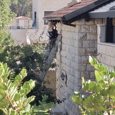 אדם על סולם עובד על גג בית אבן
