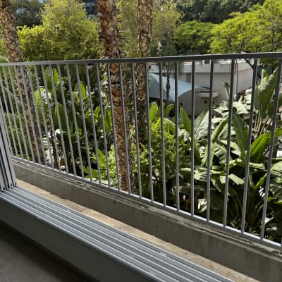 מעקה מתכת עם מסגרת חלון פתוחה ליד צמחייה ירוקה
