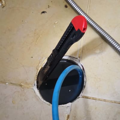 כלי עבודה וצינור כחול בתהליך תיקון נזילה ברצפה