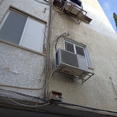 מזגן מותקן על קיר חיצוני עם חוטים חשופים