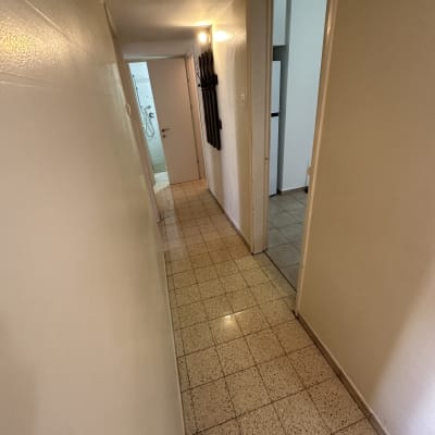 מסדרון עם רצפה נקייה ומבריקה, דלת פתוחה לחדר רחצה