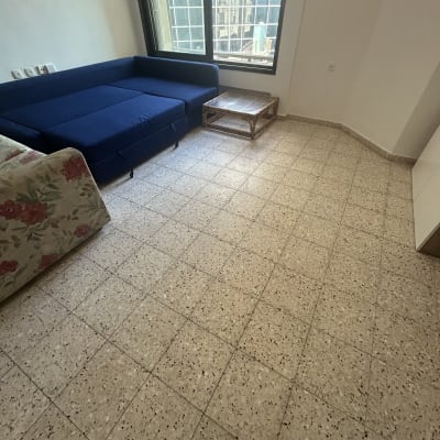 חדר עם ספה כחולה ושולחן קטן על רצפת אריחים