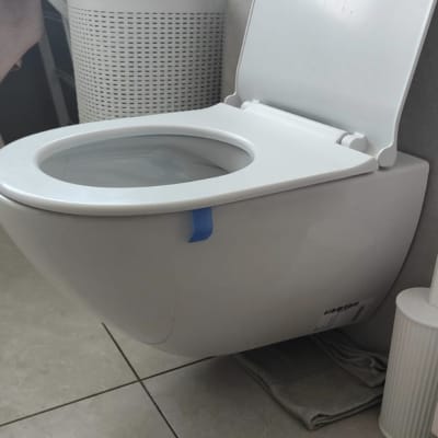 אסלה תלויה בחדר אמבטיה עם מגבות וסל כביסה