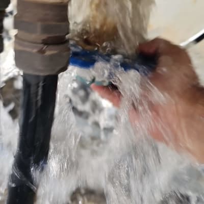 יד אוחזת בצינור עם מים זורמים