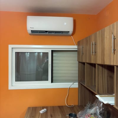 מזגן מותקן על קיר כתום בחדר עם שולחן עץ