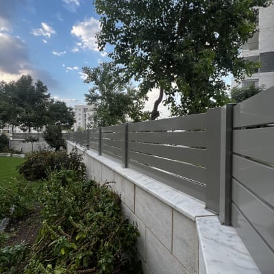 גדר עץ בגינה עם צמחייה ועצים ברקע