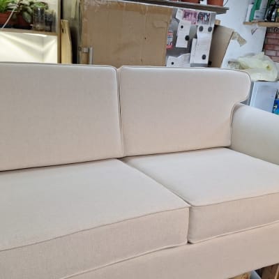 ספה מרופדת בבד בהיר עם כריות ישיבה