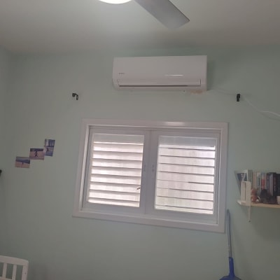 מזגן מותקן על קיר מעל חלון עם תריסים