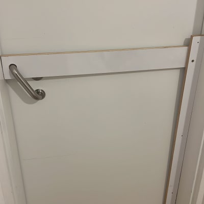 דלת עם ידית מתכת ומוט עץ אופקי