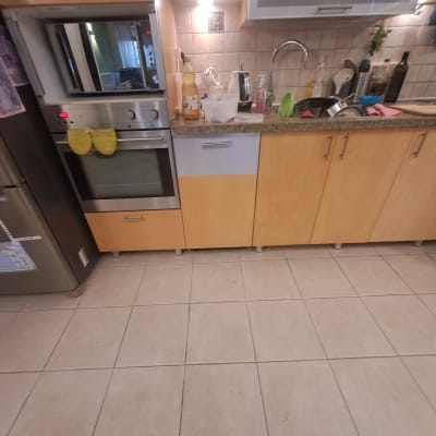 מטבח עם ארונות עץ, כיור וברז, תנור ומכשירי חשמל.